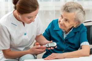 nurse checks senior woman's glucose levels